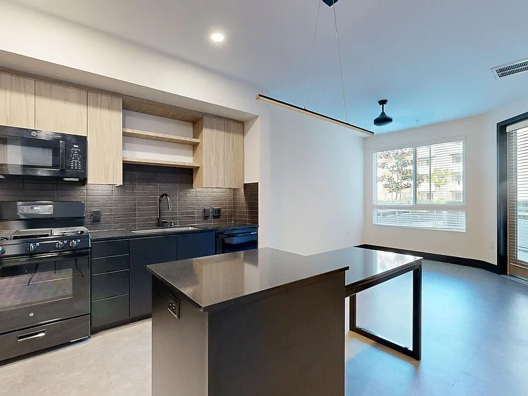 Apartment kitchen with black appliances, dark counters, and tile floor.
