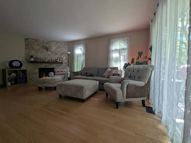 Living room with a fireplace and an accent travertine wall. Windows are facing the Spring creek