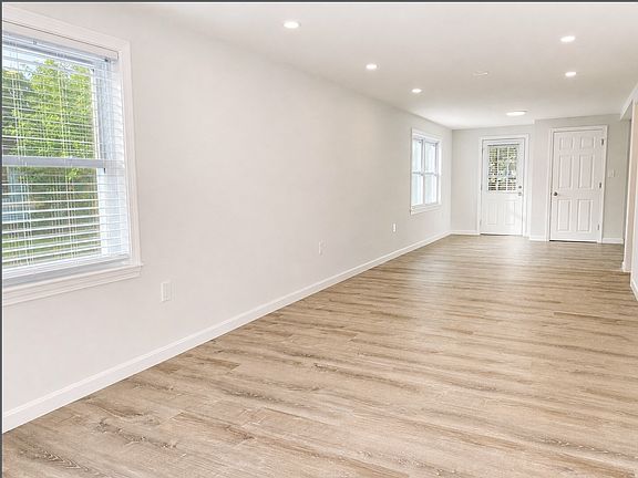 Open concept living room/dining area with luxury flooring and recessed lights.