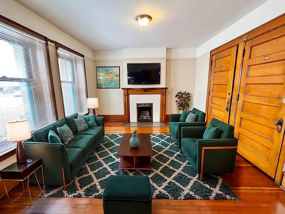 Inviting living room featuring elegant wood accents, plush green sofas, and a cozy fireplace, perfect for relaxation and gatherings.