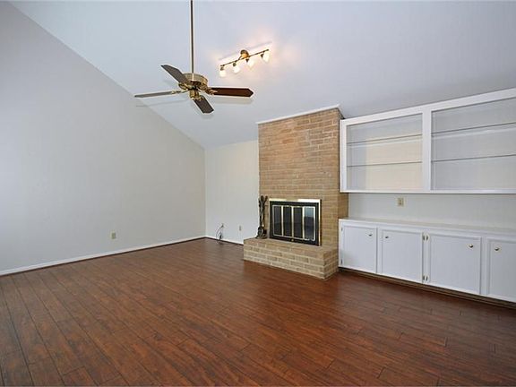 Another living room view featuring the brick fireplace and a great wall of built-ins!