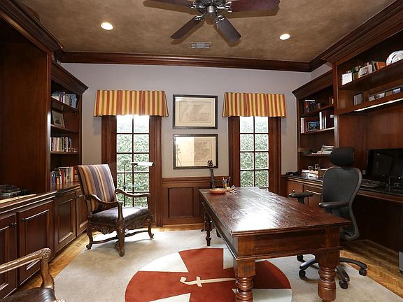 Handsome Study off the wide hallway has the perfect amount of paneling, custom stained built-ins, ra