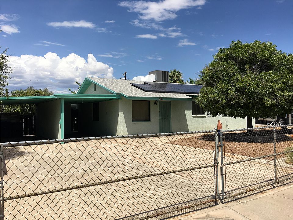 Front of home featuring gated access, paved drive way to car ports, and fruit trees. Solar & AC.
