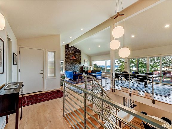 Facing the front door, there is natural light, view, and open spaces stairs leading to the lower level of this 2-story home. 