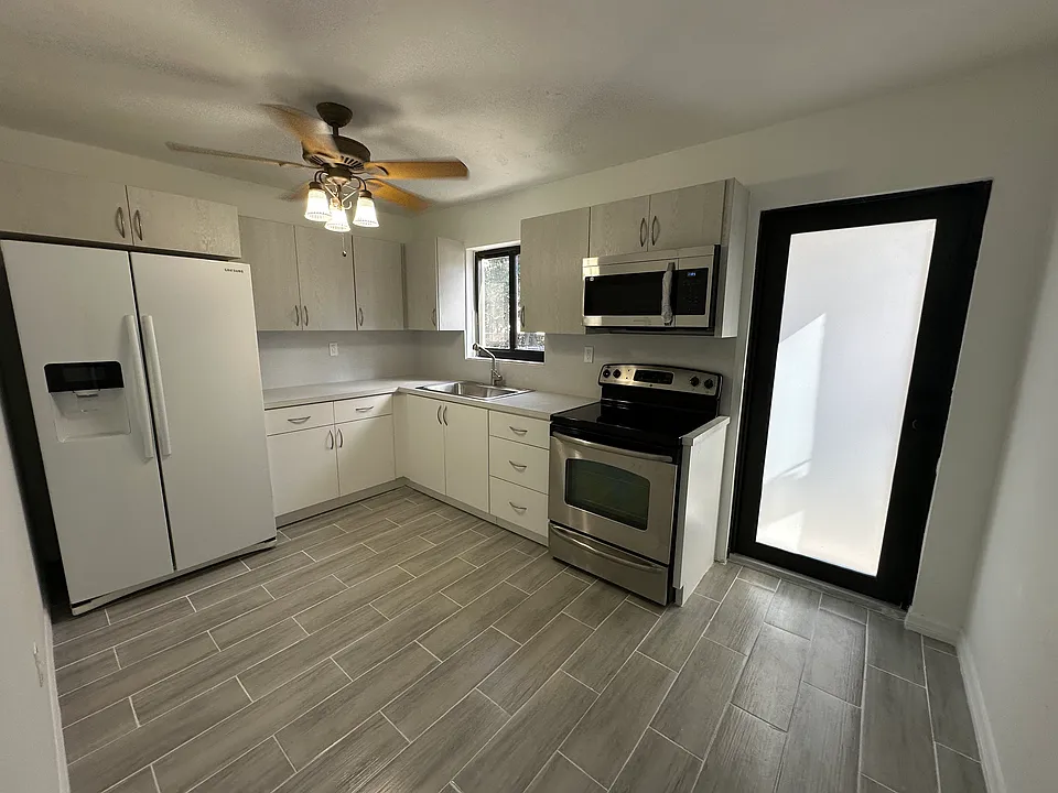 Completely Renovated Kitchen with New Cabinets. Kitchen comes with Refrigerator, Range with Oven and Microwave Oven, and Ceiling Fan.