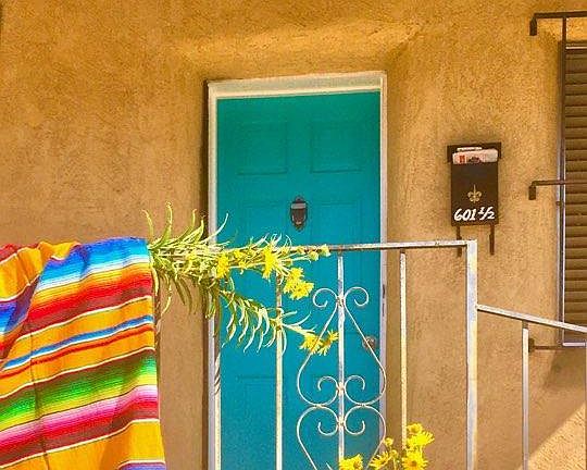 turquoise entrance door into the 1920's adobe apartment, with the portal covered front porch.