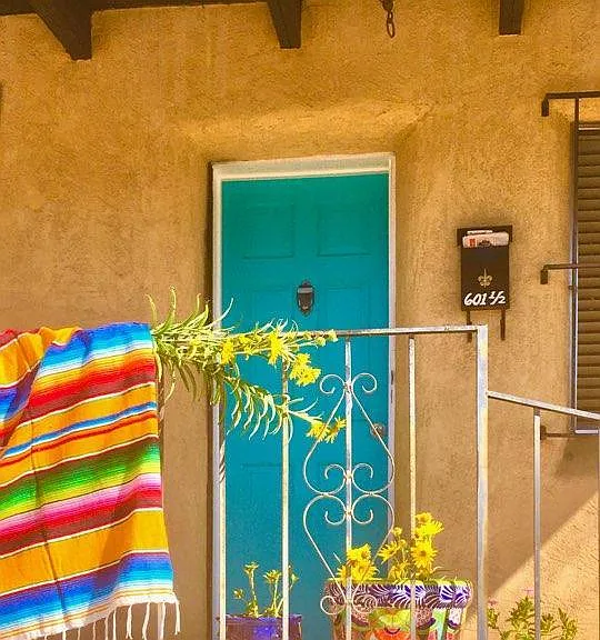 turquoise entrance door into the 1920's adobe apartment, with the portal covered front porch.