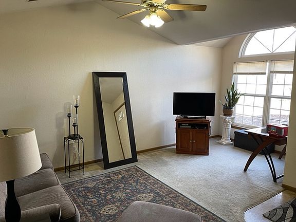 Living room with large windows and ceiling fan.