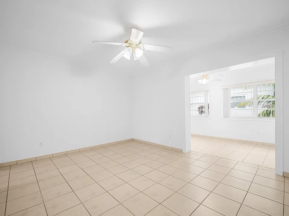 Living Room - Spacious formal living room filled with natural light, neutral ceramic tile flooring, and central air conditioning with ceiling fan.