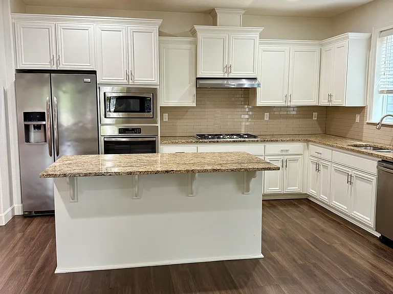 Kitchen area. Granite counter tops, stainless steel appliances, white painted cabinets