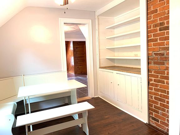 Dining room to include table and seating, built-in storage and exposed brick.