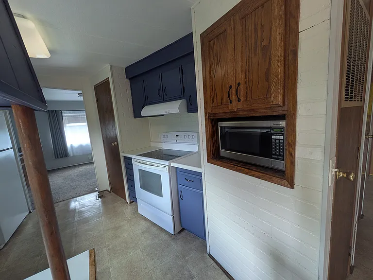 Kitchen facing microwave, oven, and pantry (far left).