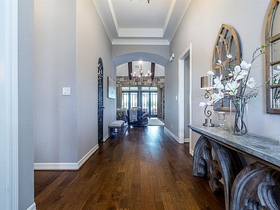 First view of this luxurious home from the front door. A beautiful chandelier hangs in the living room with the glass french doors creating a gorgeous focal point. To the left is a wine closet with a scrolled wrought iron door.