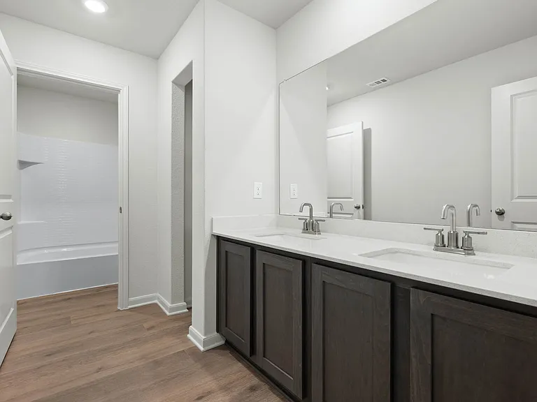 The secondary bathroom has a large vanity space and a shower-tub combo.