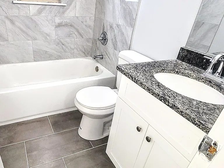 Fully remodeled bathroom with granite countertops, tile backsplash, and tiled floors