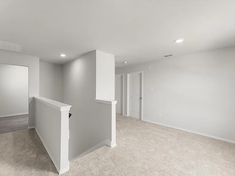 Carpeted landing area featuring white wall paint, recessed lighting, white doors with panel detailing, and a white balustrade