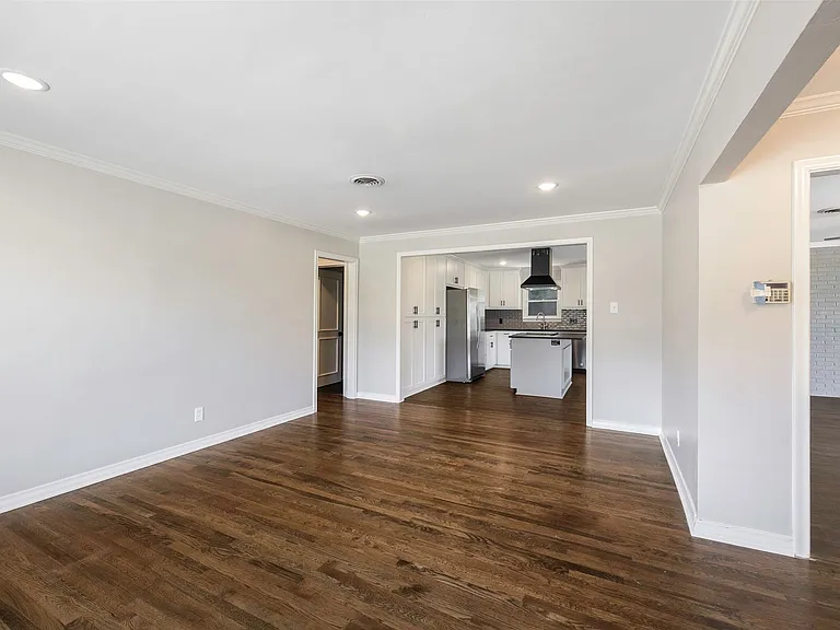 Unfurnished living room with crown molding, sink, and dark hardwood / wood-style flooring