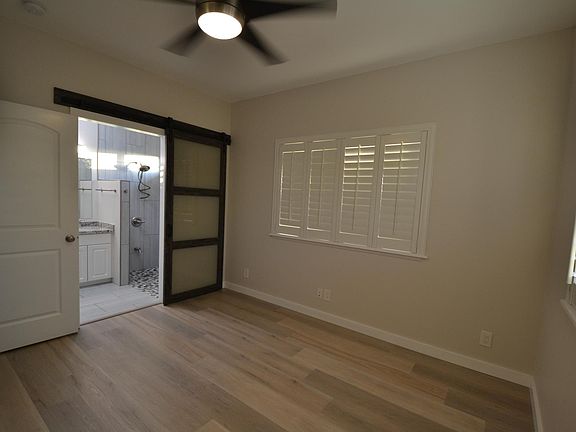 Master bedroom with split a/c, barn door, 6' closet ceiling fan with light, and ceiling to floor tiled shower.