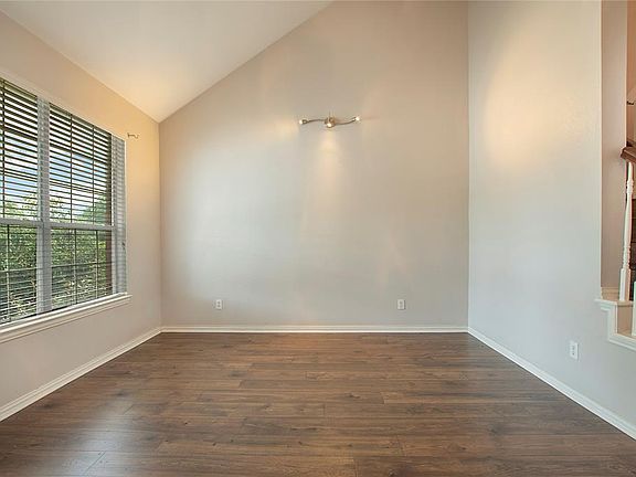 Spare room with lofted ceiling, dark wood-style floors, and stairs