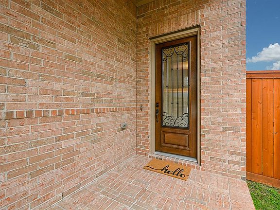 Covered entry with elegant front door accented with glass and iron scroll detailing.