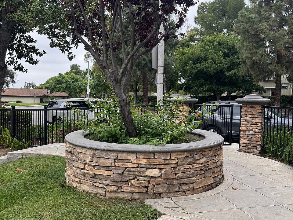 Nice gated entry with round stacked stone planter and tree.
