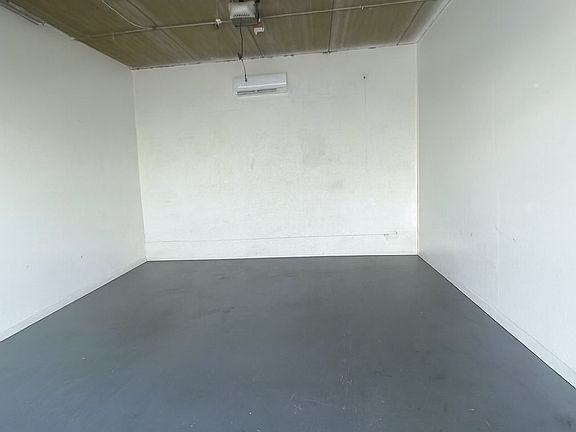 315 sq. ft. warehouse interior with gray concrete floor, white walls, new automatic garage door, AC unit, and bright fluorescent lighting.