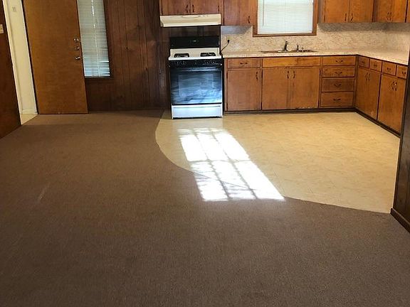 Open concept living, dining, kitchen with stove & refrigerator.