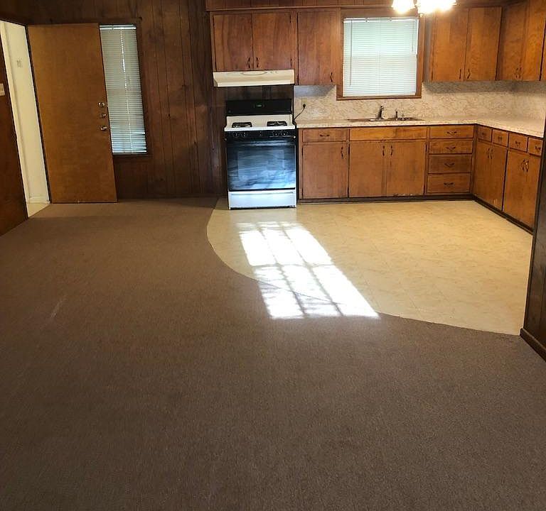 Open concept living, dining, kitchen with stove & refrigerator.