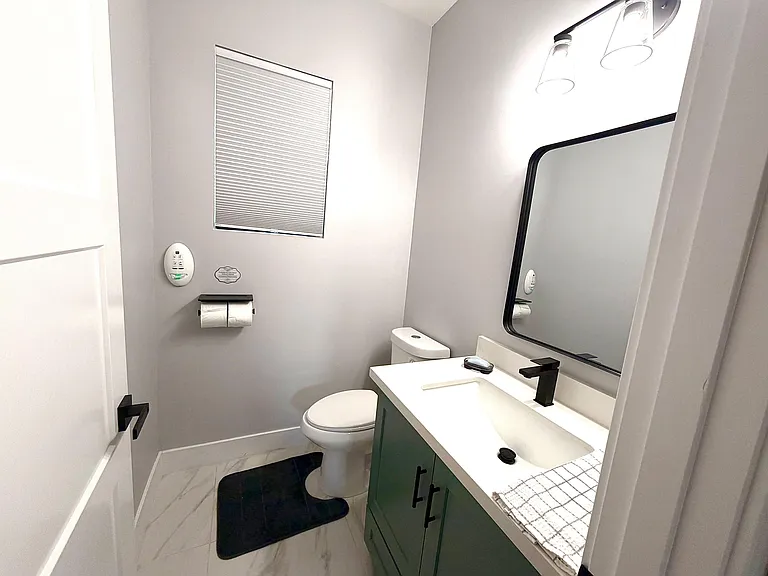 Updated bathroom with a single-sink vanity, framed mirror, and shower/tub combo, double toilet, plus a window for ventilation