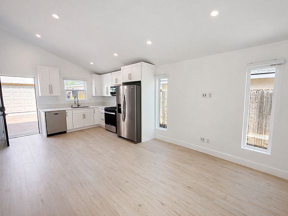 Bright open-concept living and kitchen area with recessed lighting, modern finishes, and abundant natural light.
