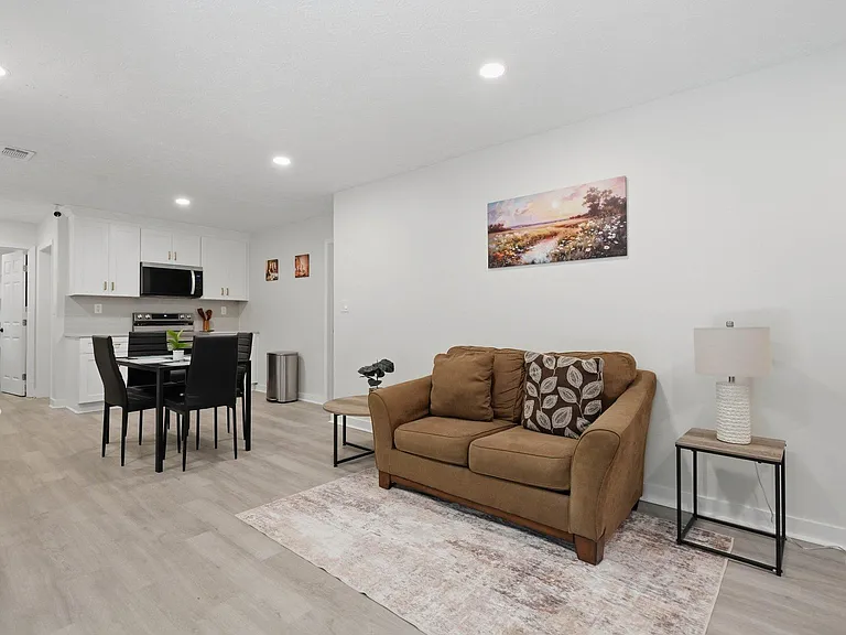 Open-concept living area with comfortable seating, dining space, and a white-cabinet kitchen with stainless appliances.