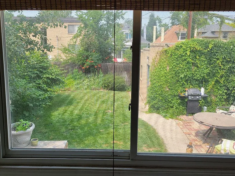 View from the sunroom of the fenced-in private backyard , garage, and paved patio
