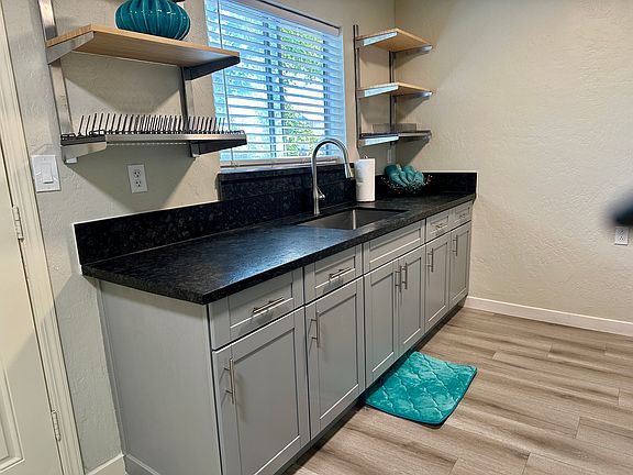 New cabinetry and stainless steel bamboo upper shelving, with dish racks on both right and.
