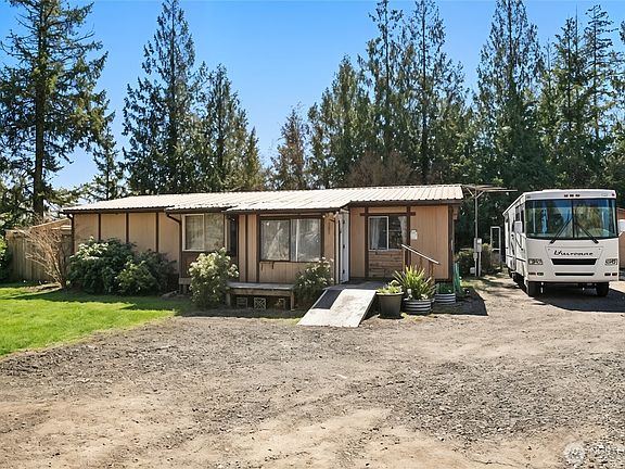 Front view of the home with bushes added for staging. Home sits on a spacious, backing forestry land.>