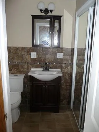 Awesome ceramic, walled sink area, with overhead lighting, beautiful, expresso mirror, toilet, tub and shower surround. mirrored, sliding door closet.