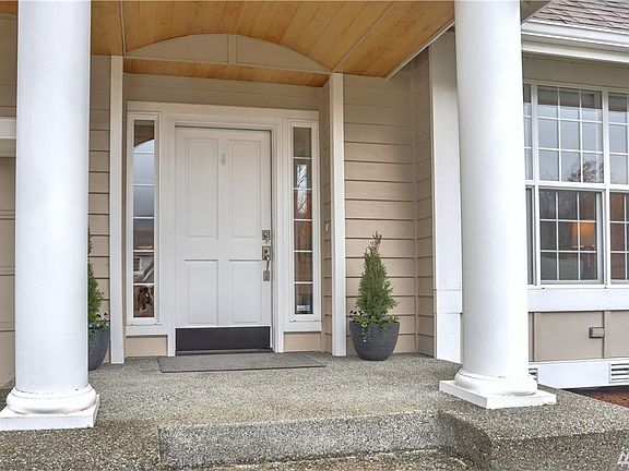 Stately covered porch flanked by columns with a cheery bright door to welcome guests.