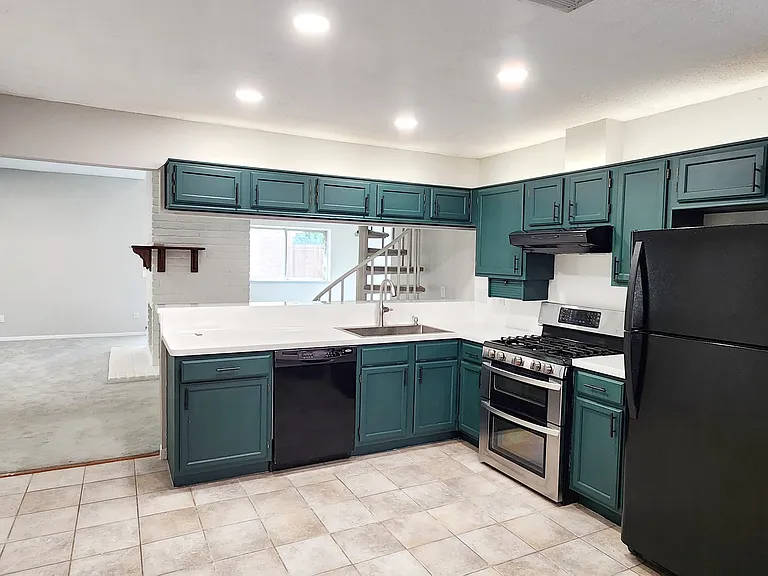 Beautiful contemporary forest green and white kitchen with ambient lighting above cabinets.