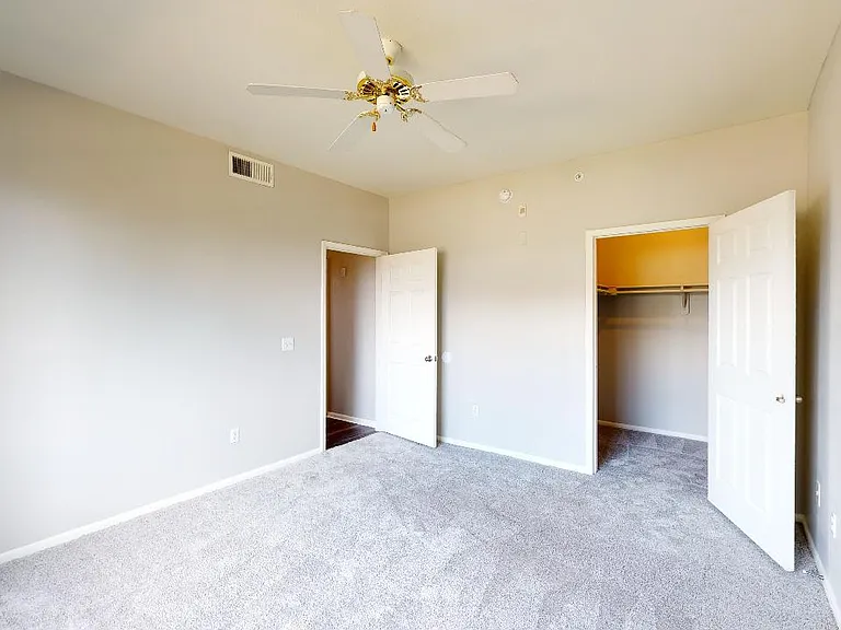 Spacious apartment bedroom with plush carpet flooring.