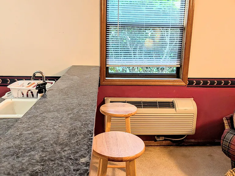 Kitchen counter with sink, breakfast seating, and a window for natural light plus in-room AC for comfort.