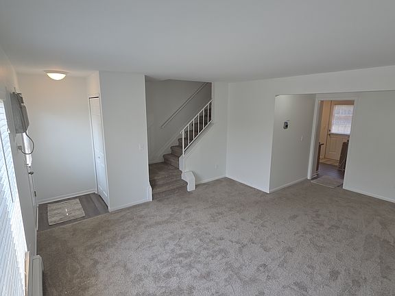 Spacious, freshly painted living room with new carpeting and access to the kitchen and second level.
