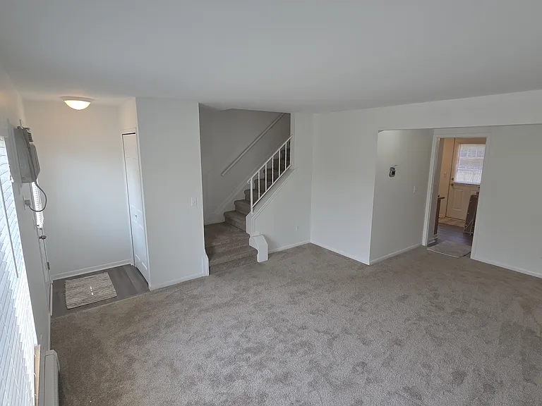 Spacious, freshly painted living room with new carpeting and access to the kitchen and second level.