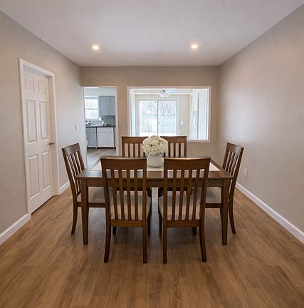 Large dining room opening to a spacious kitchen and bright sunroom, featuring brand-new luxury vinyl flooring throughout. Newly Painted. Photo has been virtually staged.