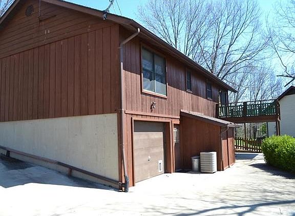 rear of home showing deck, rear entry garage and storage shed
