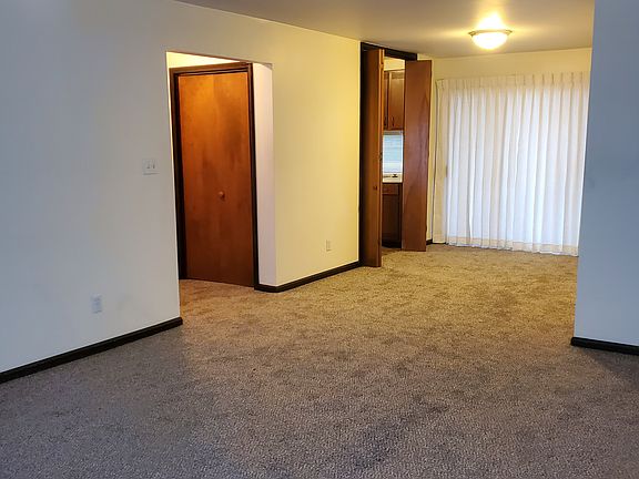 view from living room to entry on left, kitchen at center, and sliding door to rear (south)