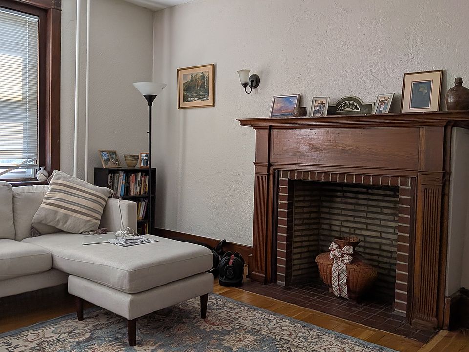 Large living room overlooking Main St with an ornamental, original fireplace