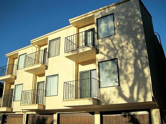 Backside view of side-by-side 3-unit building & garages, sidewalk access from around both sides as well as front, easy driving access to driveways & garages