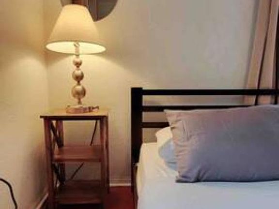 Sleeping area with a metal bed frame, nightstand, and bedside lamp for convenient lighting and personal storage.