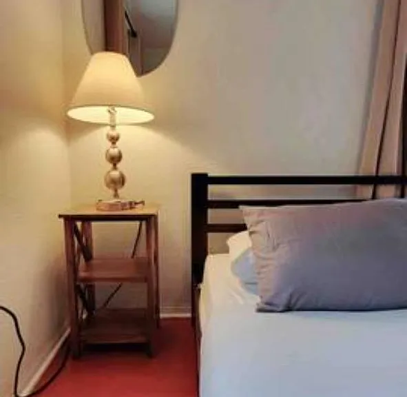 Sleeping area with a metal bed frame, nightstand, and bedside lamp for convenient lighting and personal storage.