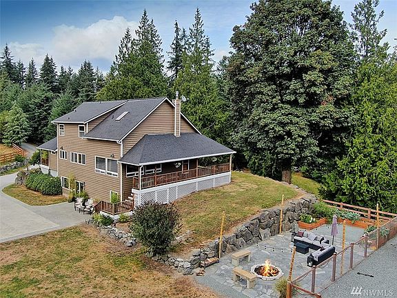 View of front entry porch and entertaining patio with fire pit, raised beds and dog run with shelter.