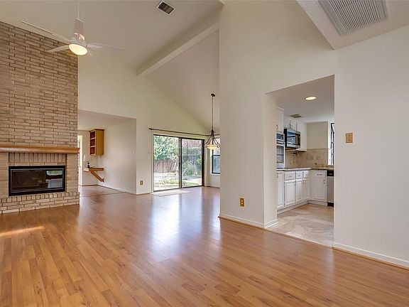 The living room has laminate wood floors, high ceilings, and a ceiling fan.